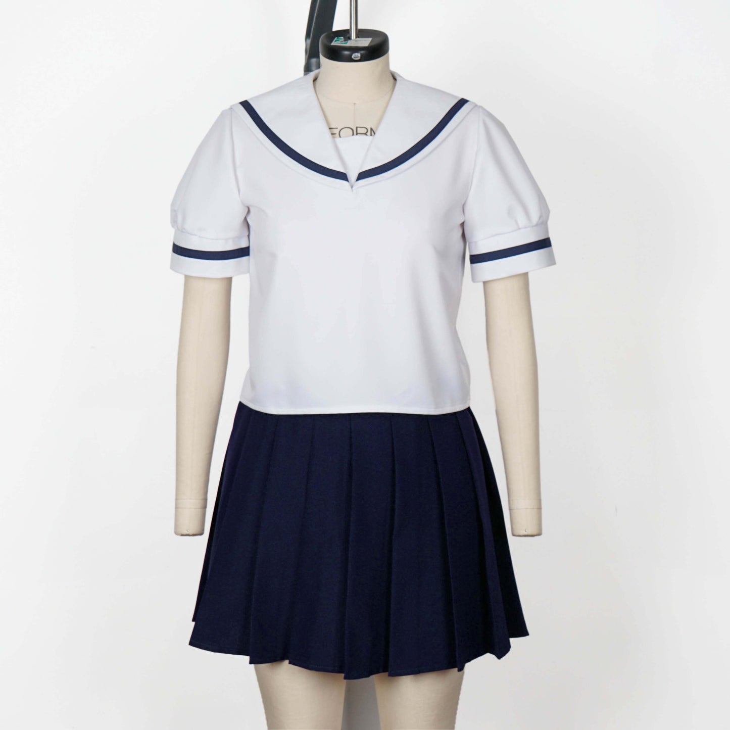 Upper body shot of a mannequin wearing a white seifuku top with a navy blue sailor collar and matching trim on the short sleeves. A dark navy blue skirt is visible beneath the top. The background is a plain white studio backdrop.