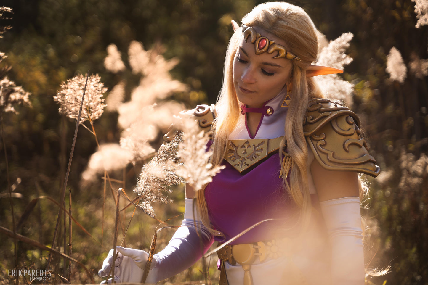 Cosplayer dressed as a fantasy princess in an enchanted forest setting, wearing a detailed gown with gold armor and elf-like features.