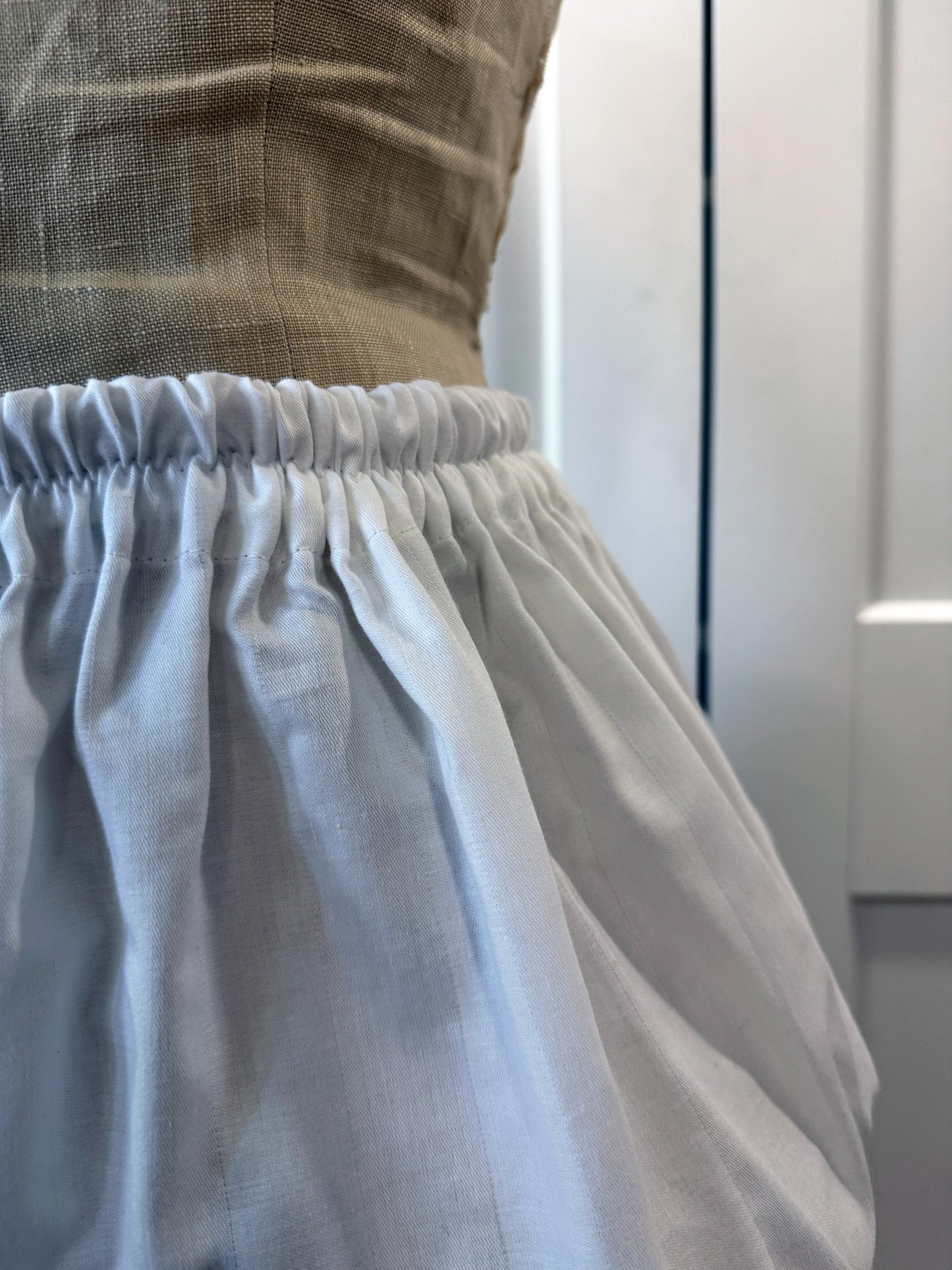a close up of ruffled shorts being displayed on a mannequin showing the elastic waistband and the topstitches in detail