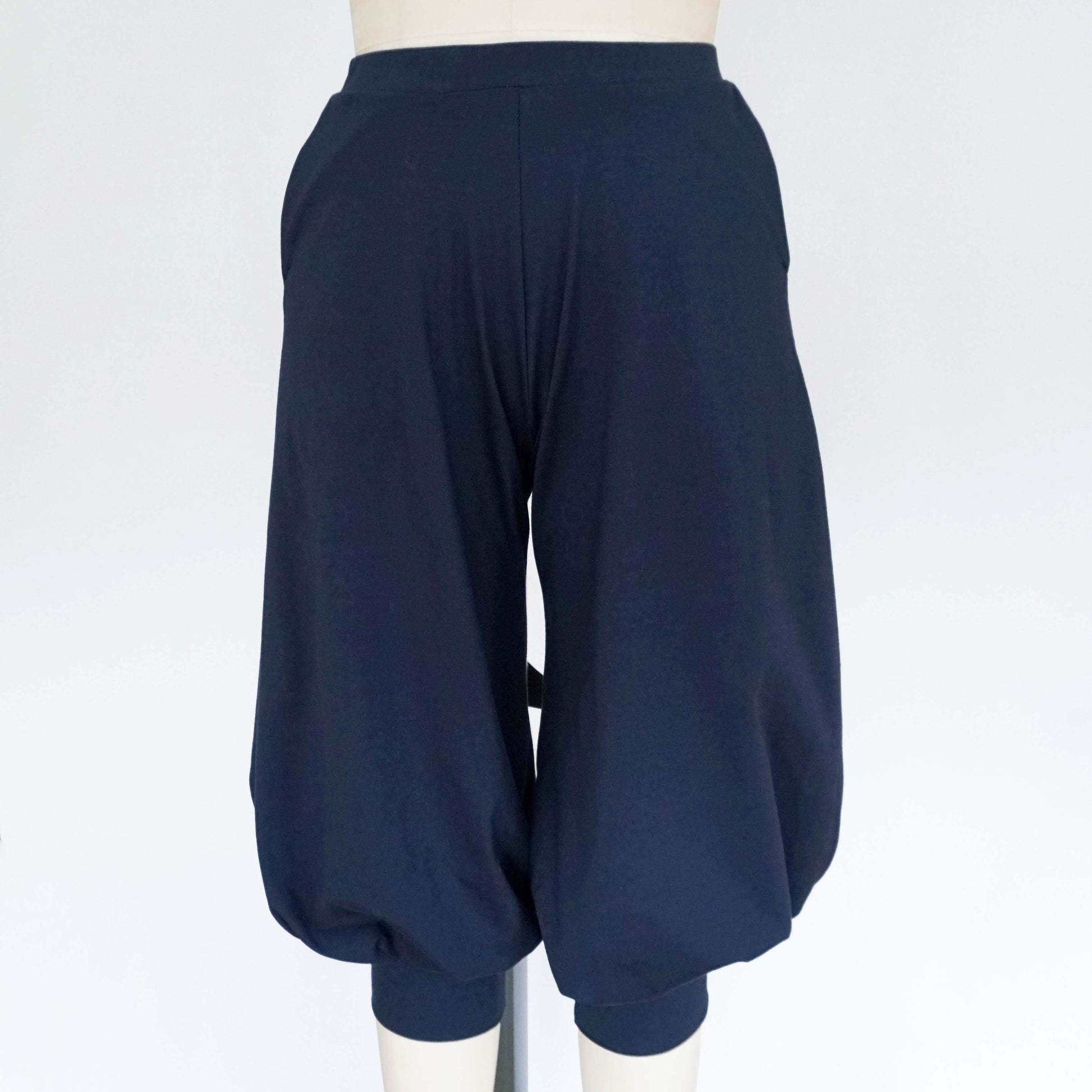 A pair of dark blue cuffed baggy pants displayed on a mannequin, featuring a loose fit and gathered ankle cuffs.