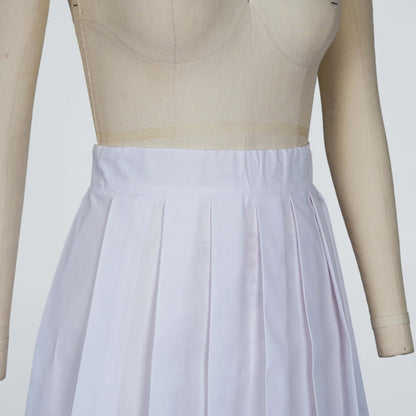 Image of a white pleated skirt being designed. The skirt is on a dress form, showcasing the garment's design and construction.