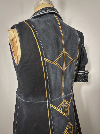 Three-quarter back view of the Lune jacket cosplay from Clair Obscur: Expedition 33 on a dress form, showing the sleeveless left side and the full back bodice and skirt with gold geometric designs spanning both panels across the waist seam. The princess seams, center back seam, and quilted collar are clearly visible. The sleeved right side with its quilted cuff and gold button is partially visible at the edge.