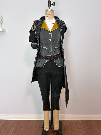 Front view of a cosplay costume on a dress form. Features a long quilted black coat with red trim, a grey button-front vest over a white shirt with gold lapels, a wide dark belt with red accents, cropped black pants, and a structured shoulder piece on the left. Displayed against a white wall.