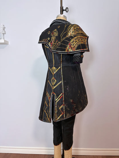 Back view of a cosplay costume on a dress form. Features a long black sleeveless coat with gold and red geometric painted detailing, a structured quilted shoulder piece with ornate gold accents, a center back vent, and black pants. Displayed against a white wall.