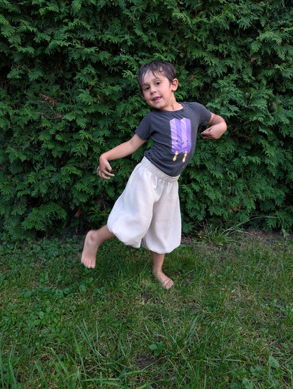 Child wearing handmade cuffed baggy pants, posing playfully outdoors.