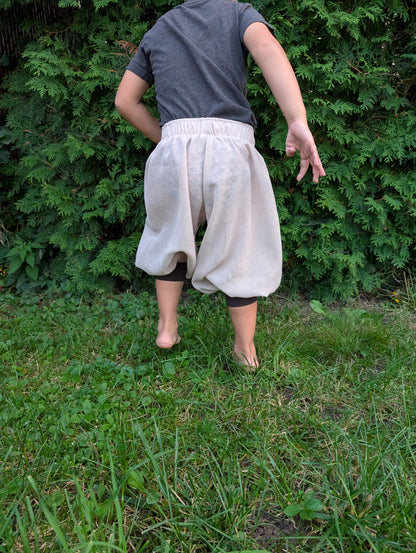Back view of a child wearing handmade cuffed baggy pants outdoors.