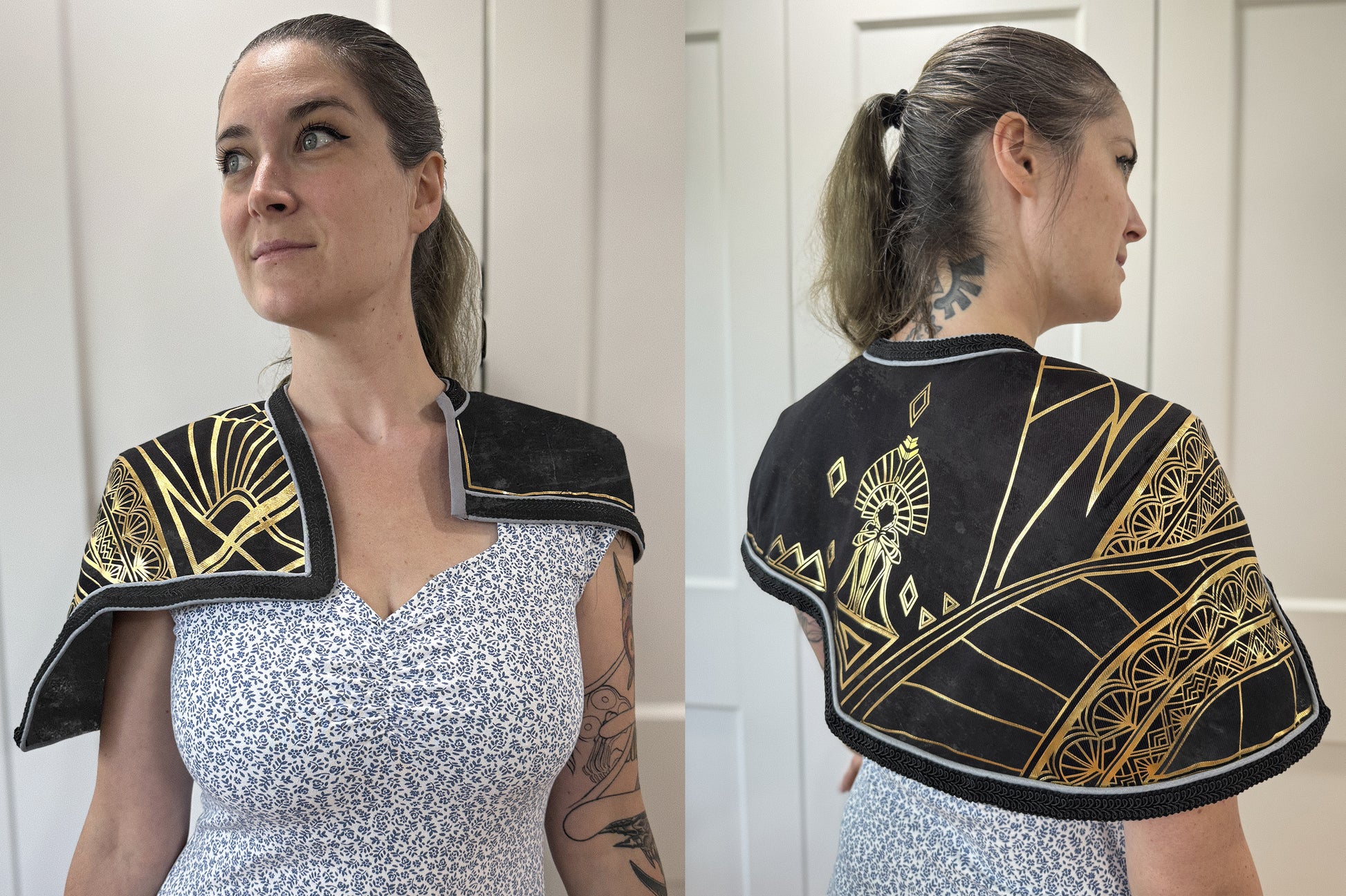 Front and back views of a black capelet worn by a person over a floral dress. The capelet features extensive gold geometric and Art Deco-style painted or HTV detailing, including fan motifs, diamond shapes, and a central figure on the back. The edges are finished with a fine red trim.