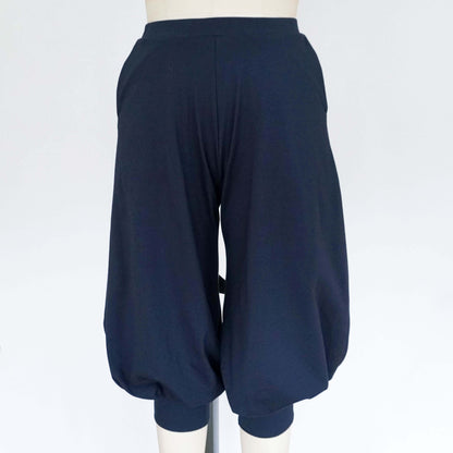 A pair of dark blue cuffed baggy pants displayed on a mannequin, featuring a loose fit and gathered ankle cuffs.